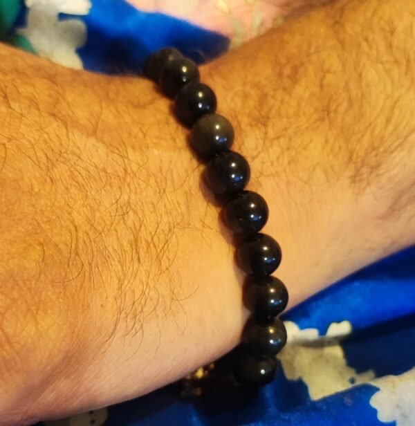 Bracelet en perles d'obsidienne noire naturelle porté au poignet, bijou élégant et protecteur
