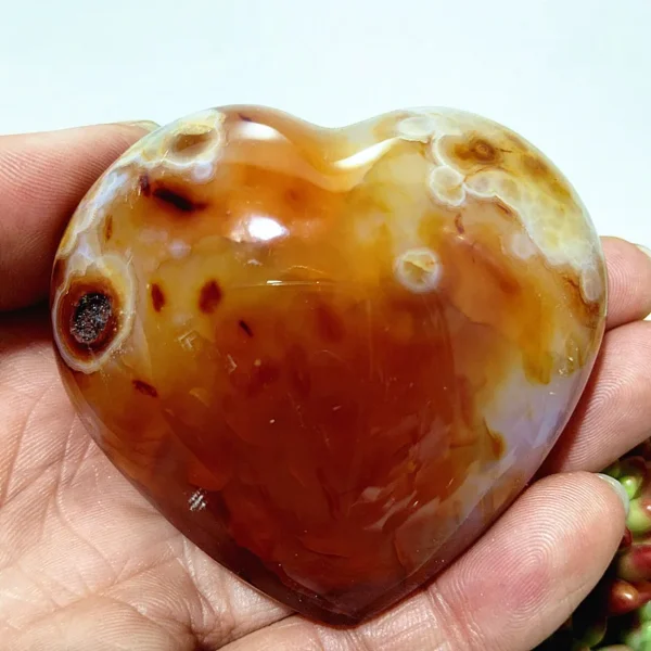 Cœur en agate naturelle avec nuances d'orange et de beige, motifs naturels uniques, symbole d'harmonie et de bien-être, tenu en main