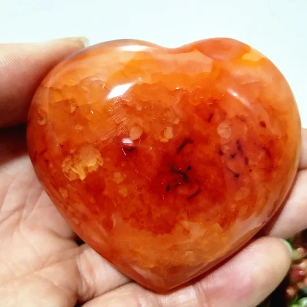 Cœur en agate naturelle avec nuances vibrantes d'orange, symbole de vitalité et d'équilibre, tenu en main