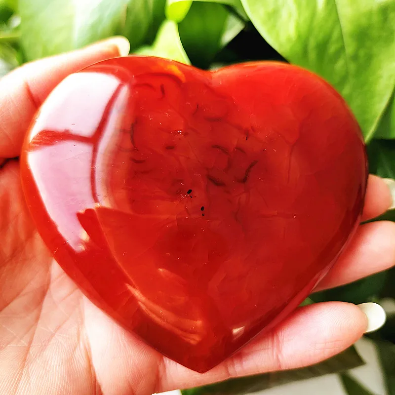 coeur-agate-rouge-naturelle-cristal-bien-etre Cœur en agate rouge naturelle, symbole d'amour et de bien-être, tenu en main avec des nuances profondes de rouge