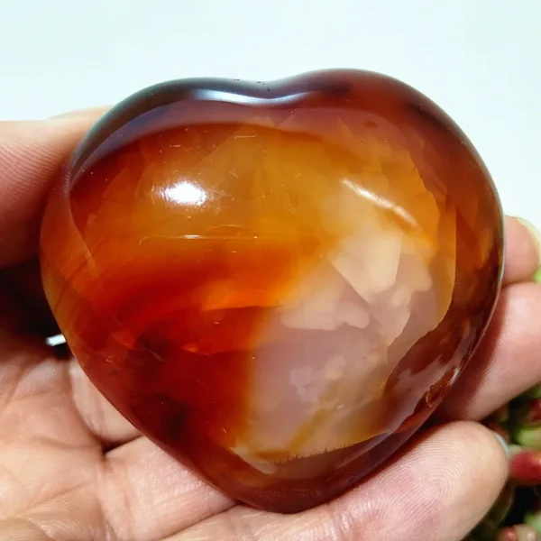 Cœur en agate rouge naturelle, symbole d'équilibre et d'énergie, nuances de rouge, orange et brun, tenu en main