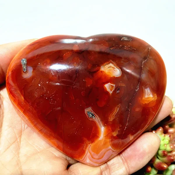 Cœur en agate rouge naturelle, pierre de vitalité et d'harmonie, nuances rouges profondes avec inclusions, tenu en main
