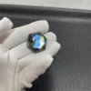 Cristal de labradorite hexagonal avec des reflets bleus irisés, tenu par une main gantée sur un fond texturé.