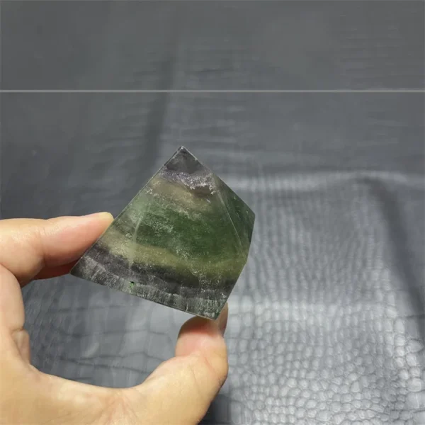 Cristal de quartz arc-en-ciel en fluorite naturelle, forme de pyramide verte et violette, tenu en main.