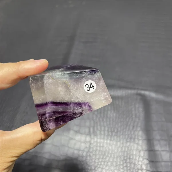 Cristal de quartz en fluorite arc-en-ciel avec transparence et nuances violettes, tenu en main.