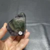 Cristal de quartz en fluorite naturelle, avec des teintes de vert profond et de violet, tenu en main.