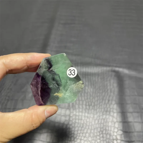 Cristal de quartz en fluorite arc-en-ciel avec transparence et teintes vertes et violettes, tenu en main.