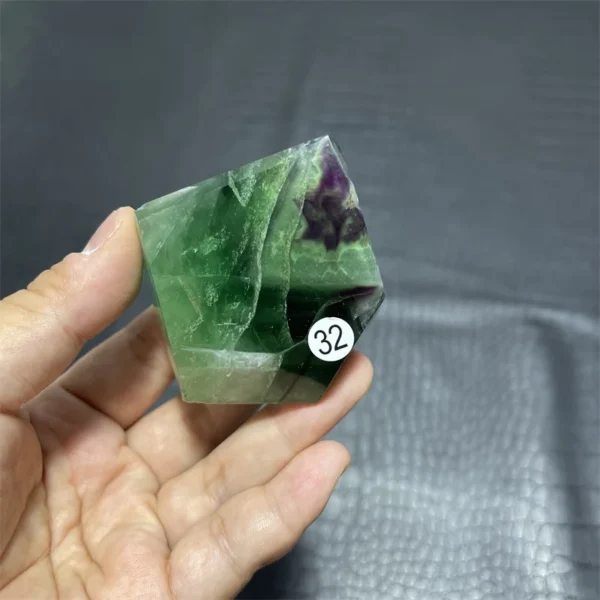 Cristal de quartz en fluorite arc-en-ciel naturel avec des teintes vertes et violettes, tenu en main.