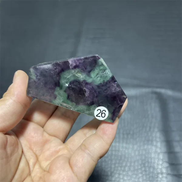 Cristal de quartz en fluorite naturelle avec des nuances de violet et de vert, tenu en main.