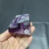 Cristal de quartz en fluorite naturelle avec des nuances de violet et de blanc, tenu en main pour montrer sa taille.