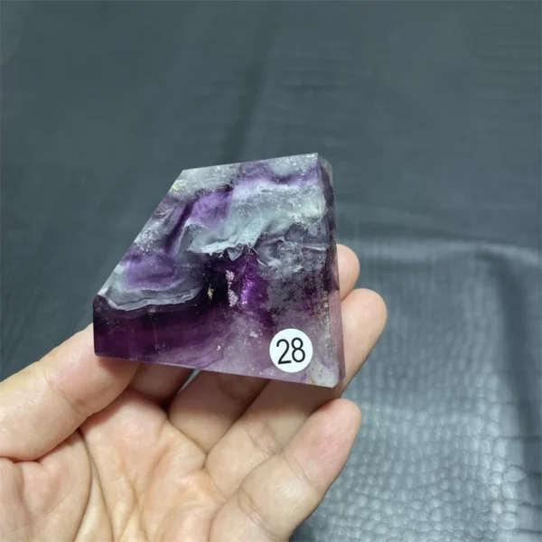 Cristal de quartz en fluorite naturelle avec des nuances de violet et de blanc, tenu en main pour montrer sa taille.