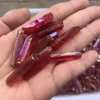 Cristaux de quartz lémurien Aura Arc-en-Ciel Rouge iridescents dans la main, montrant des reflets vibrants.