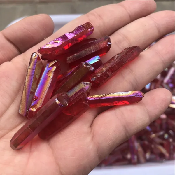 Cristaux de quartz lémurien Aura Arc-en-Ciel Rouge iridescents dans la main, montrant des reflets vibrants.
