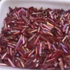 Gros plan sur des cristaux de quartz lémurien Aura Arc-en-Ciel Rouge en vrac dans un plateau, parfaits pour la guérison et la décoration.
