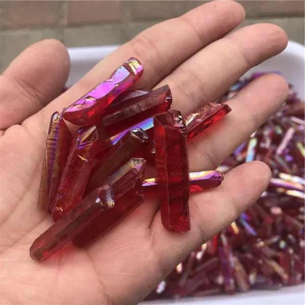 Cristaux de quartz lémurien Aura Arc-en-Ciel Rouge tenus dans une main, montrant leur éclat iridescent.
