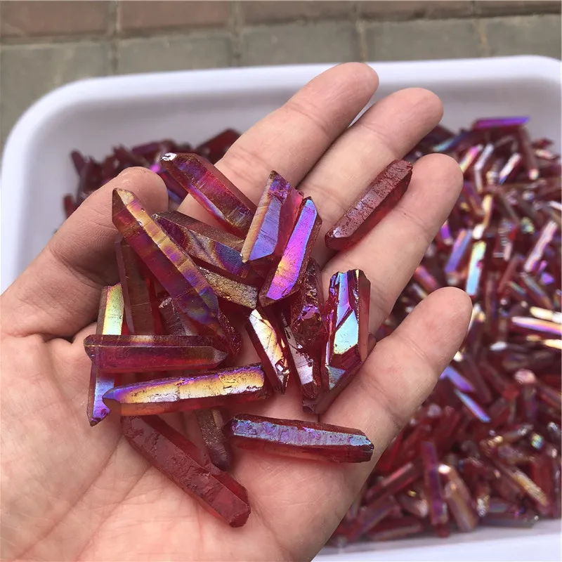 cristaux-quartz-lemurien-aura-arc-en-ciel-rouge-titane-guérison-main Cristaux de quartz lémurien Aura Arc-en-Ciel Rouge en titane dans une main, montrant des couleurs vibrantes arc-en-ciel pour guérison et décoration.