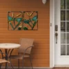 Décoration murale en forme de libellule en métal et verre, installée sur une terrasse extérieure en bois