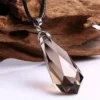 Pendentif en quartz fumé naturel facetté, suspendu à un cordon en cuir noir, avec un fond en bois rustique.