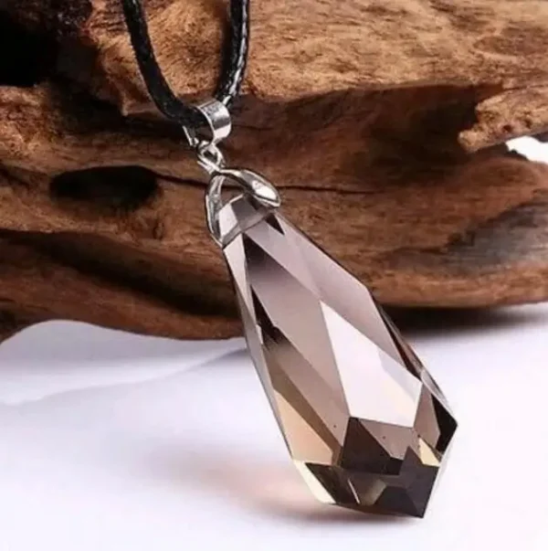 Pendentif en quartz fumé naturel facetté, suspendu à un cordon en cuir noir, avec un fond en bois rustique.