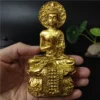 Statue de Bouddha doré en position de prière, tenue dans une main, vue détaillée