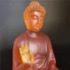 Gros plan de la statue de Bouddha en résine colorée translucide, expression sereine et posture méditative