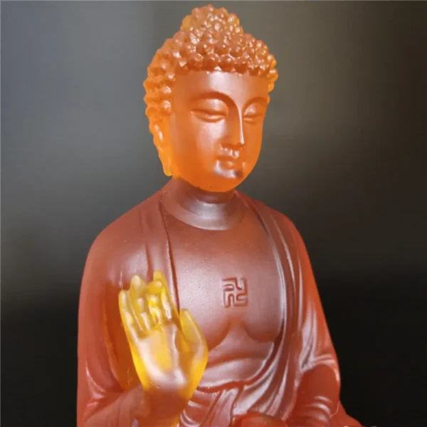 Gros plan de la statue de Bouddha en résine colorée translucide, expression sereine et posture méditative