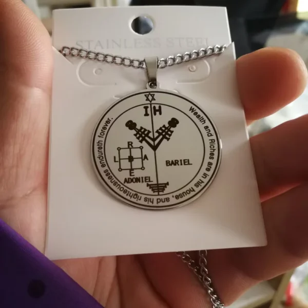 Talisman ADONIEL BARIEL en acier inoxydable, quatrième pentacle de Jupiter, tenu en main pour démontrer sa taille et sa finition.
